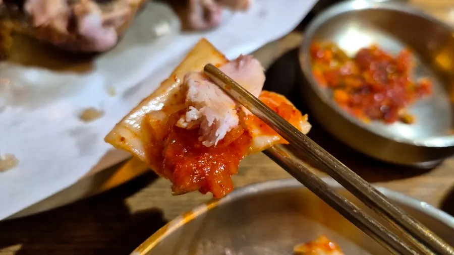 김치를 올려 먹는 장작구이 닭고기 한 점