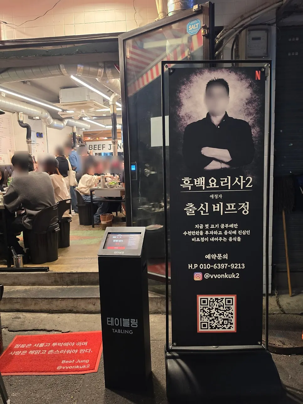 비프정 고기집 입구의 셰프 사진 배너와 테이블링 기계