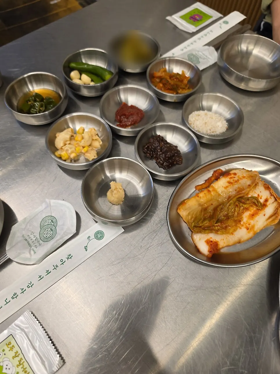 메탈 그릇에 담긴 김치와 장아찌 등 기본 밑반찬 상차림