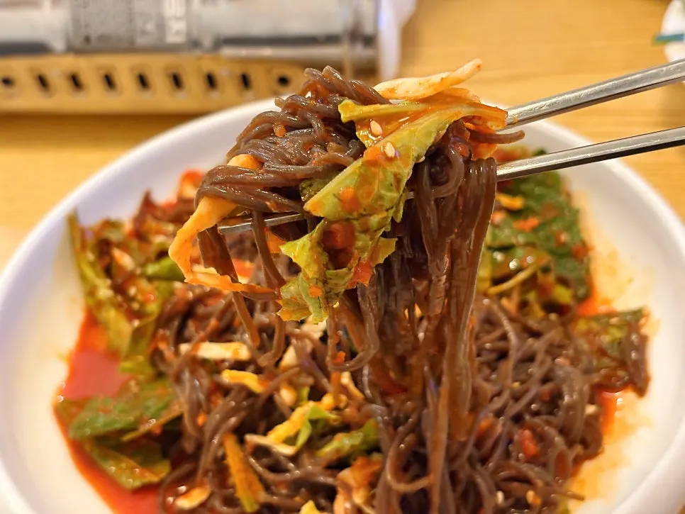 Makguksu noodles topped with egg garnish and sesame seeds
