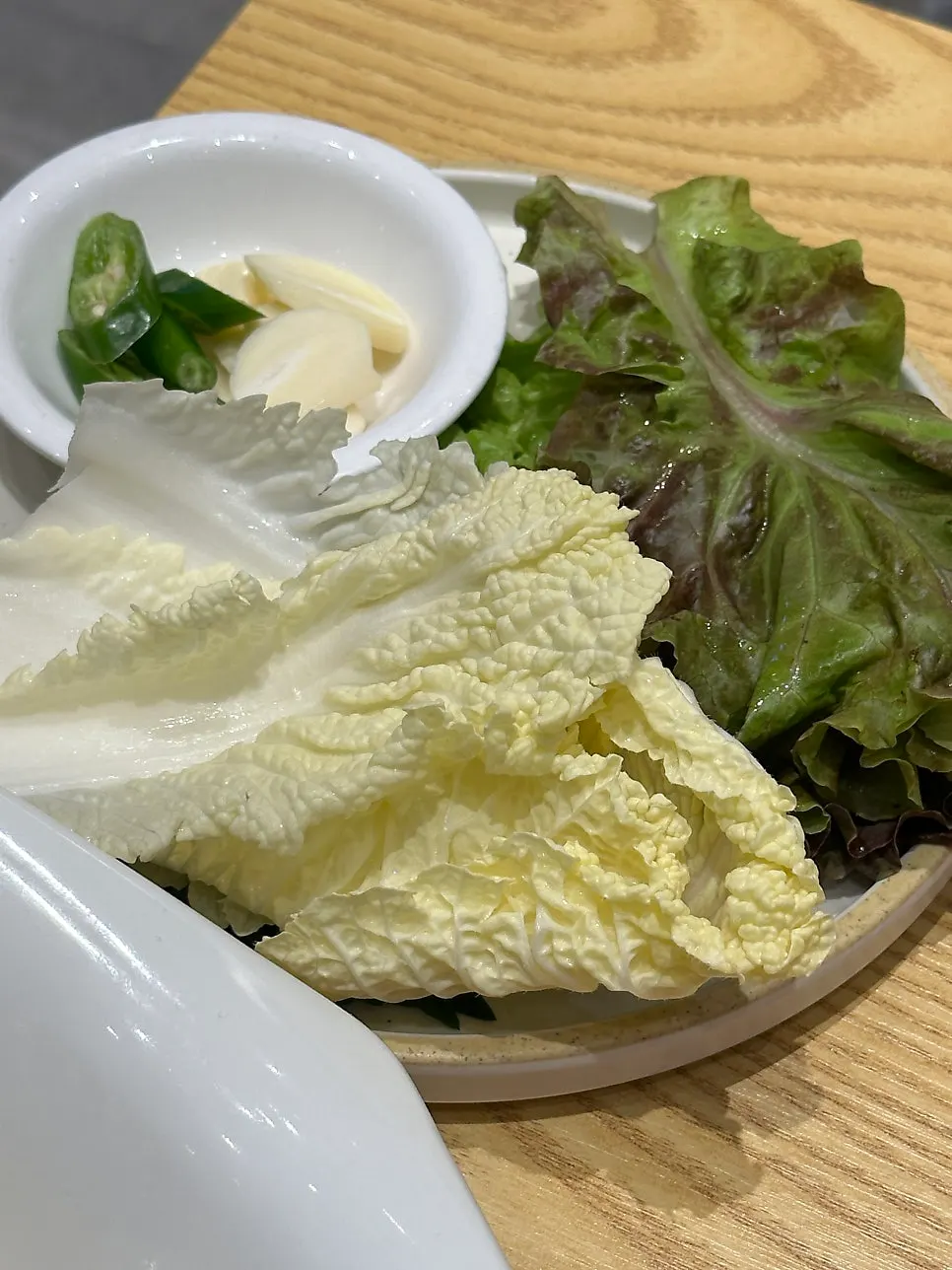 Plate of wrap vegetables with cabbage, lettuce, and perilla leaves