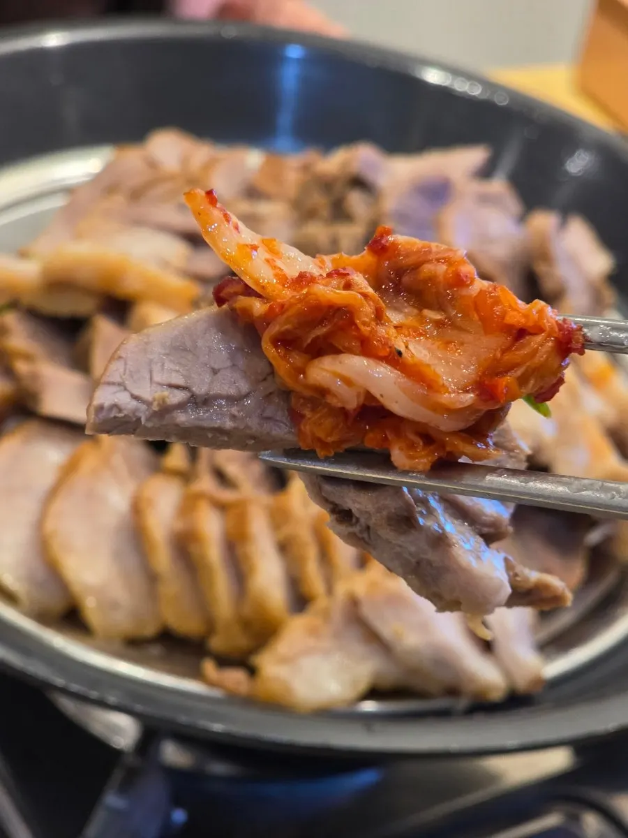 A bite of bossam wrapped with kimchi