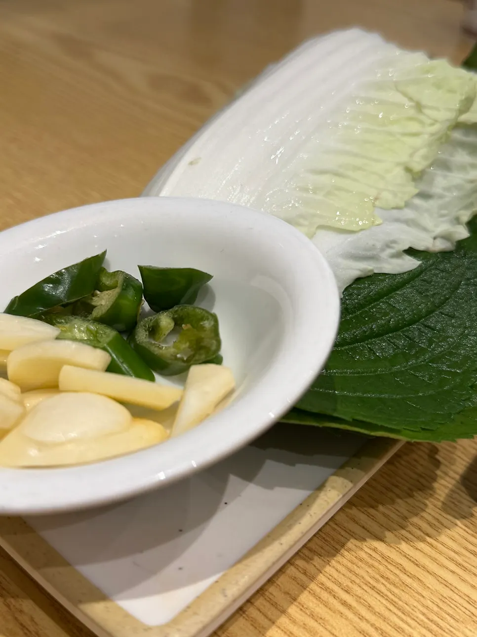 A piece of bossam topped with radish kimchi and chive salad