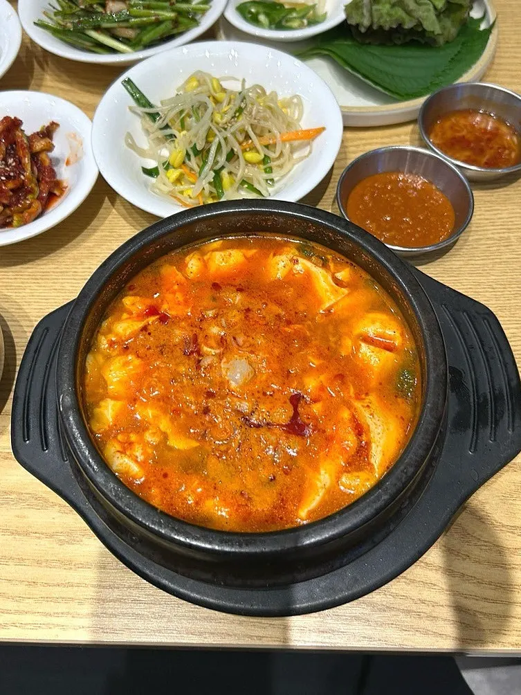 Table spread with a bubbling sundubu jjigae bossam set