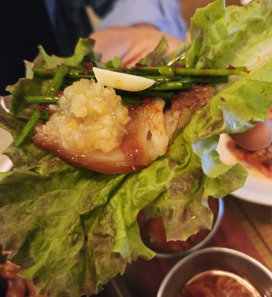 Jokbal dipped in garlic sauce with a lettuce wrap