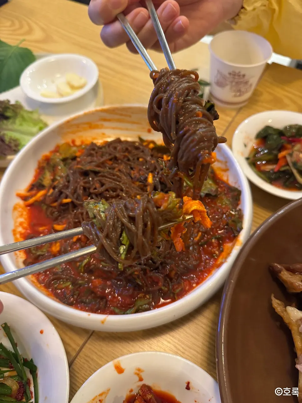 A shot glass of soju next to the jokbal