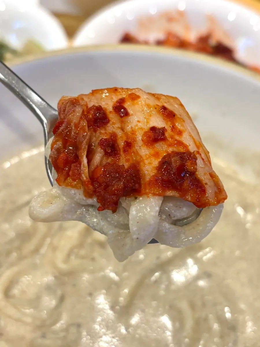 Lifting a bite of perilla kalguksu noodles