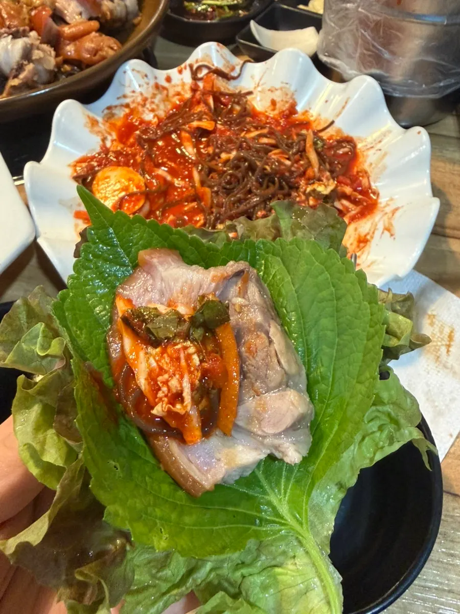 Lettuce wrap topped with jokbal and radish kimchi