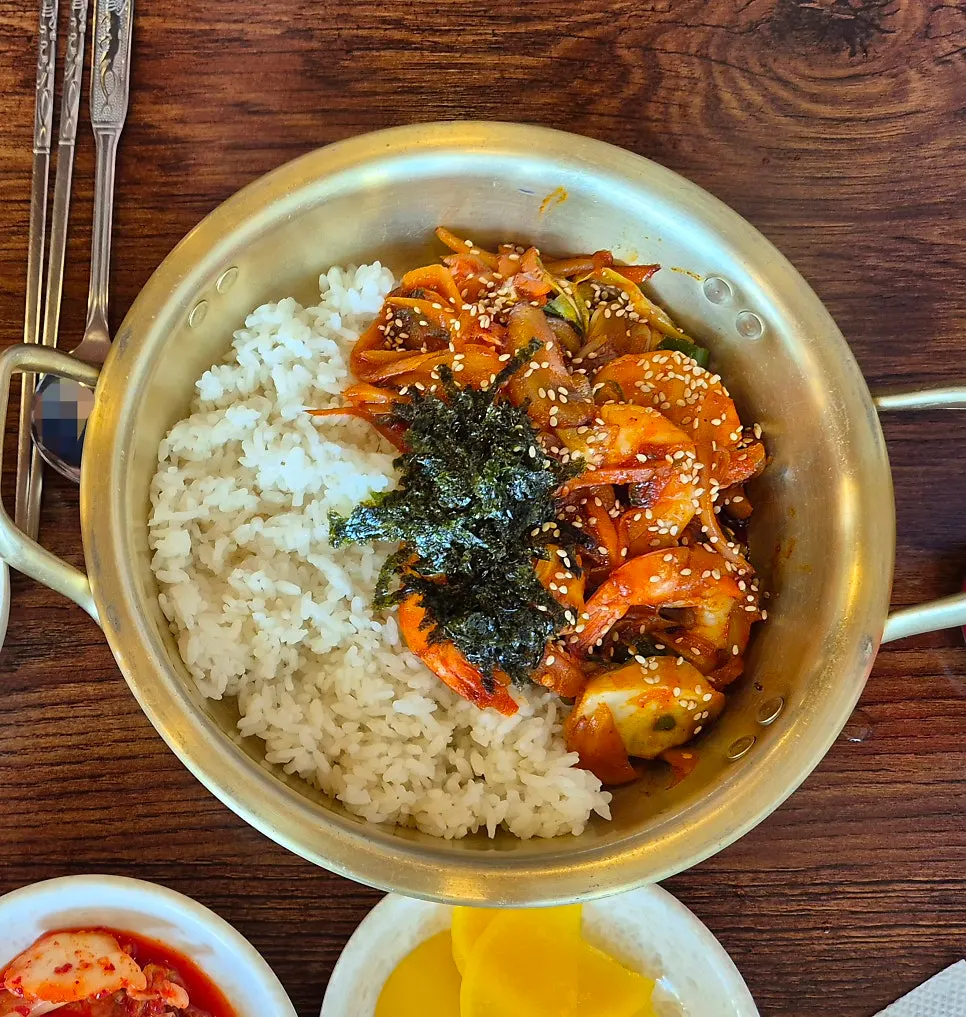 A spoonful of shrimp rice bowl mixed with sauce