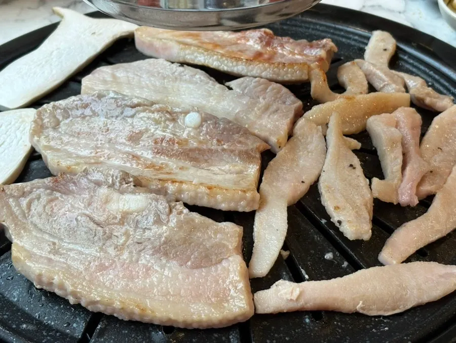 Pork belly grilling on the barbecue plate