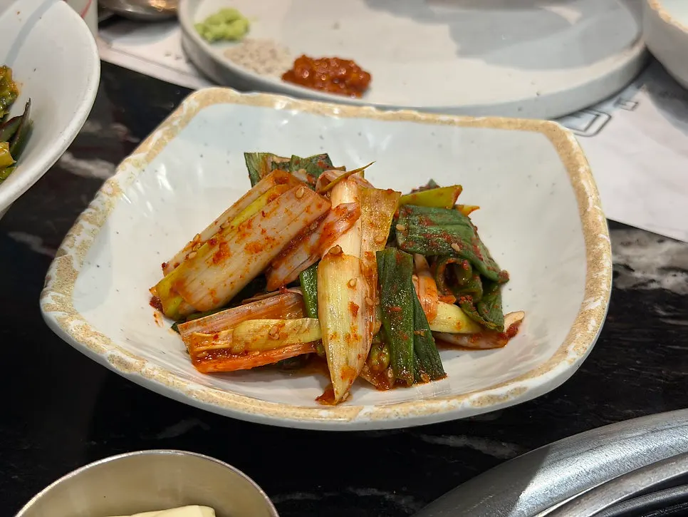Plate of fresh dressed greens, green onion kimchi, and white kimchi