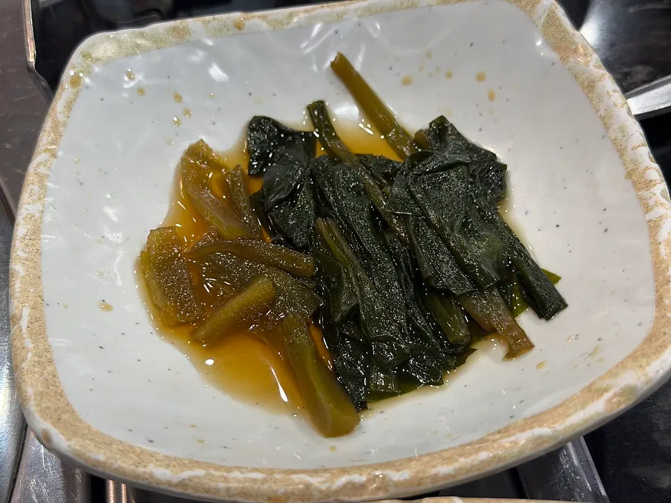 Side dishes of pickled radish, cabbage salad, and wild garlic greens