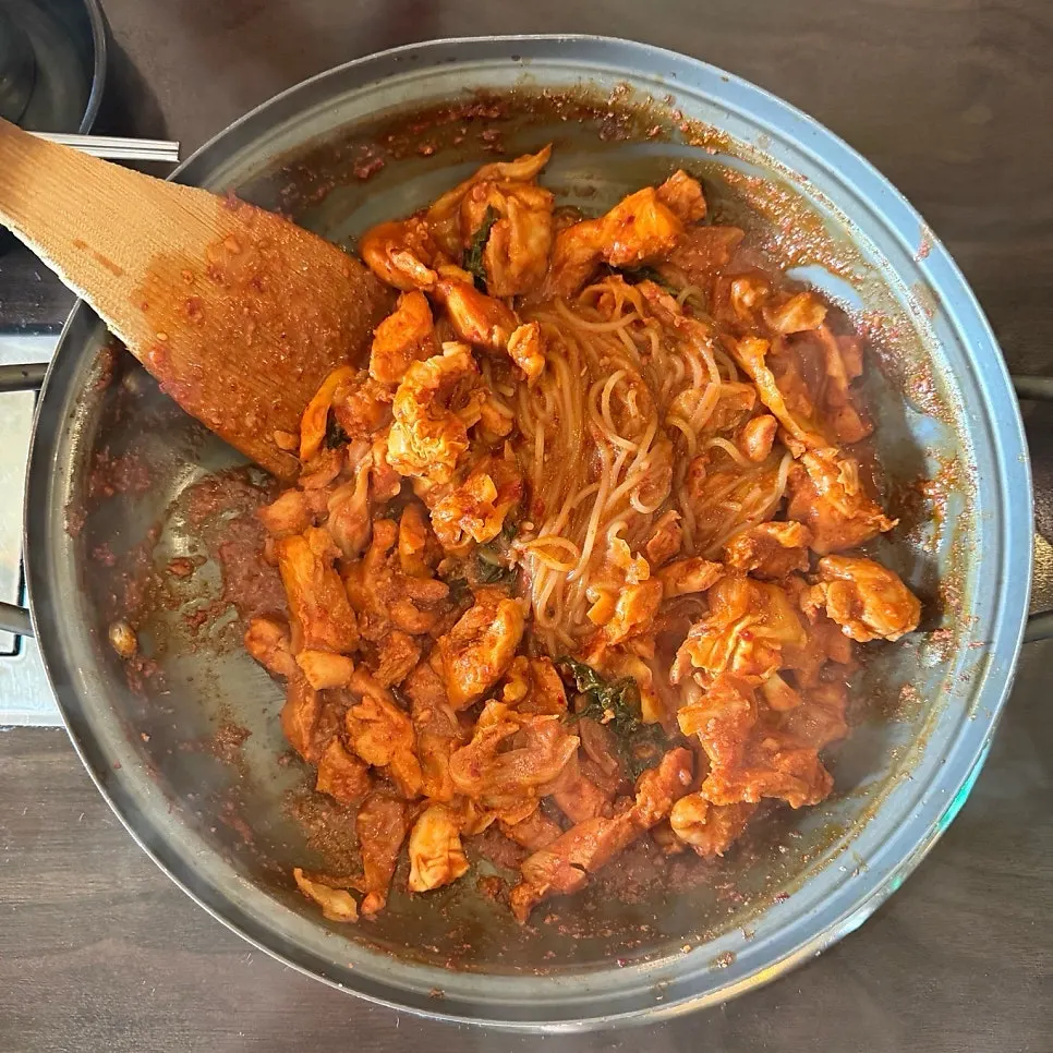 닭갈비 한 점과 쫄면을 함께 집은 모습