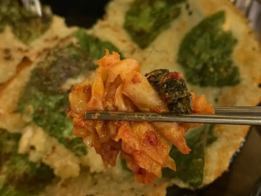 Dakgalbi wrapped in perilla-potato pancake being eaten