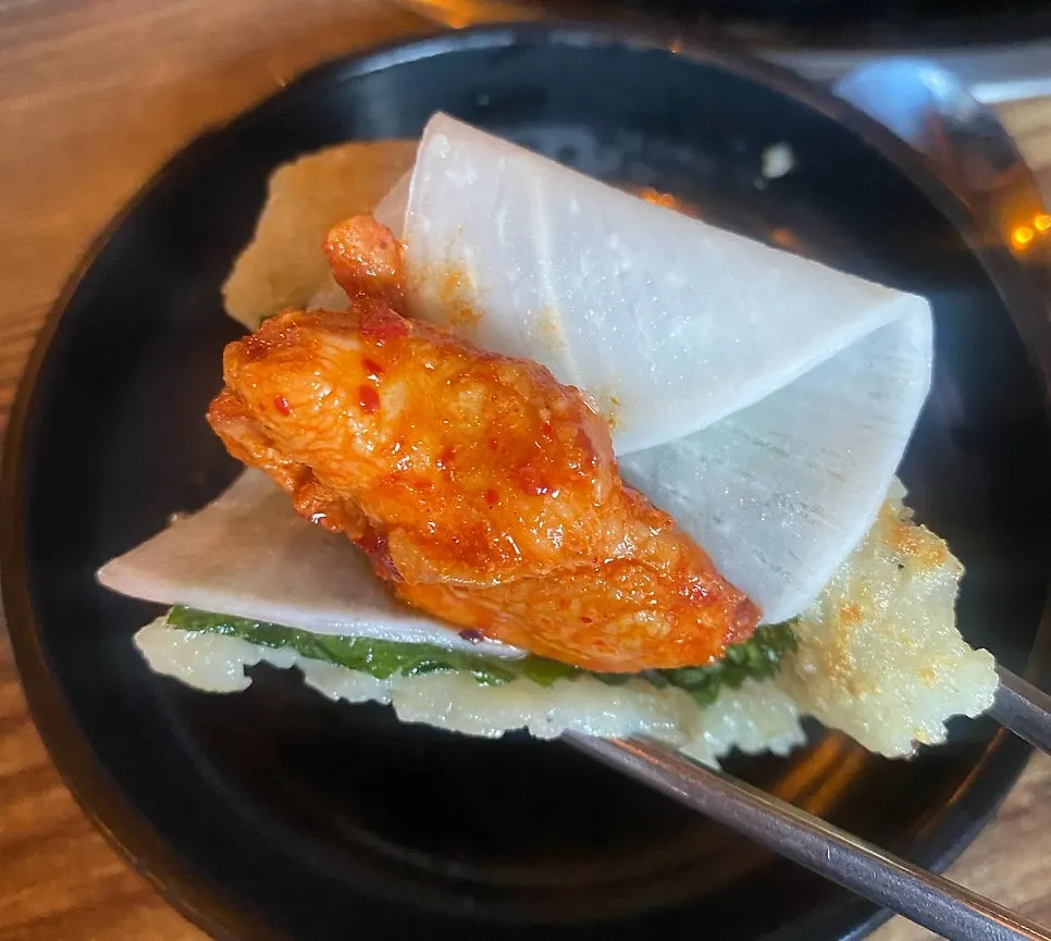 A wrap of dakgalbi with pickled radish