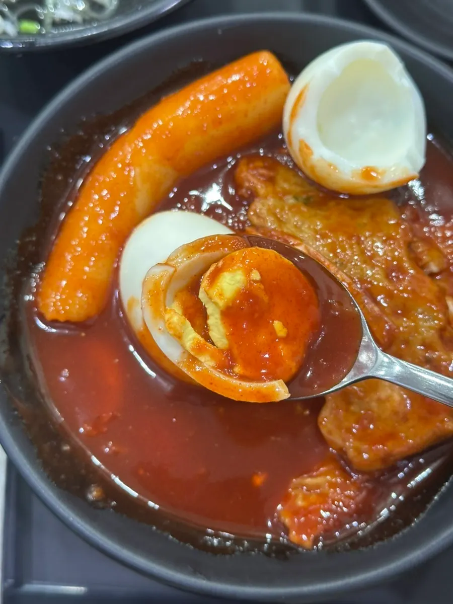 A boiled egg split in half and coated in sauce