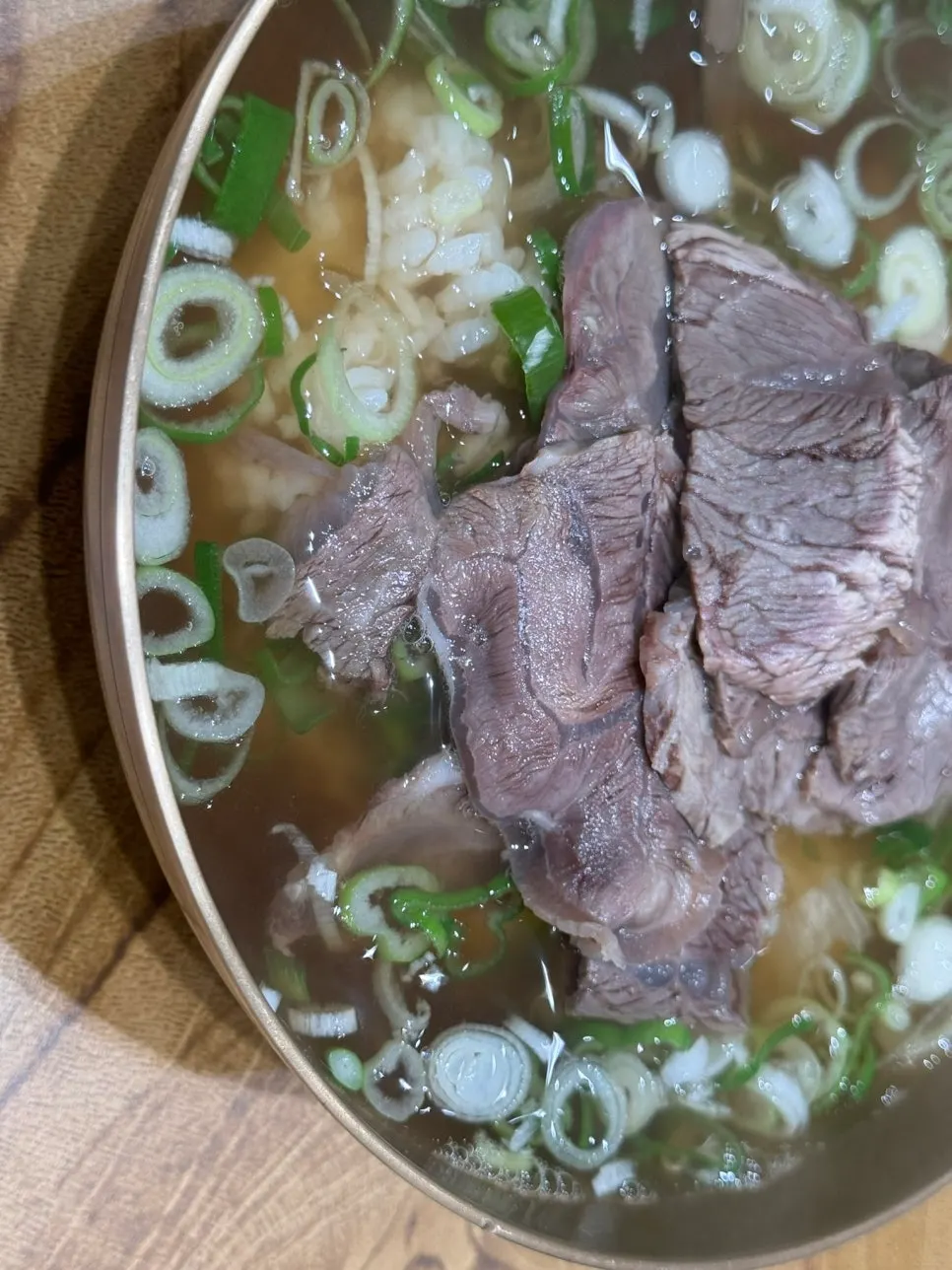Clear gomtang topped with green onion and meat