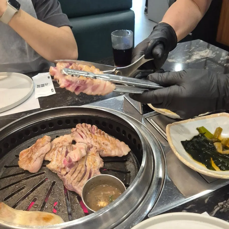 Staff member grilling thick-cut black pork geungogi