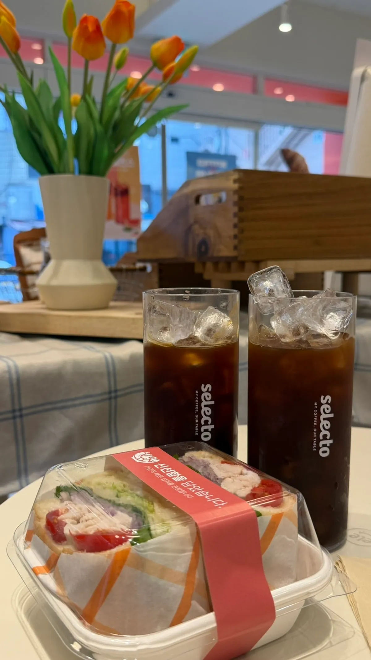 테이블에 놓인 커피 두 잔과 치킨 샌드위치