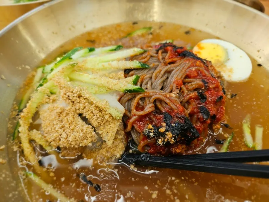 Noodles lifted up from the water makguksu bowl