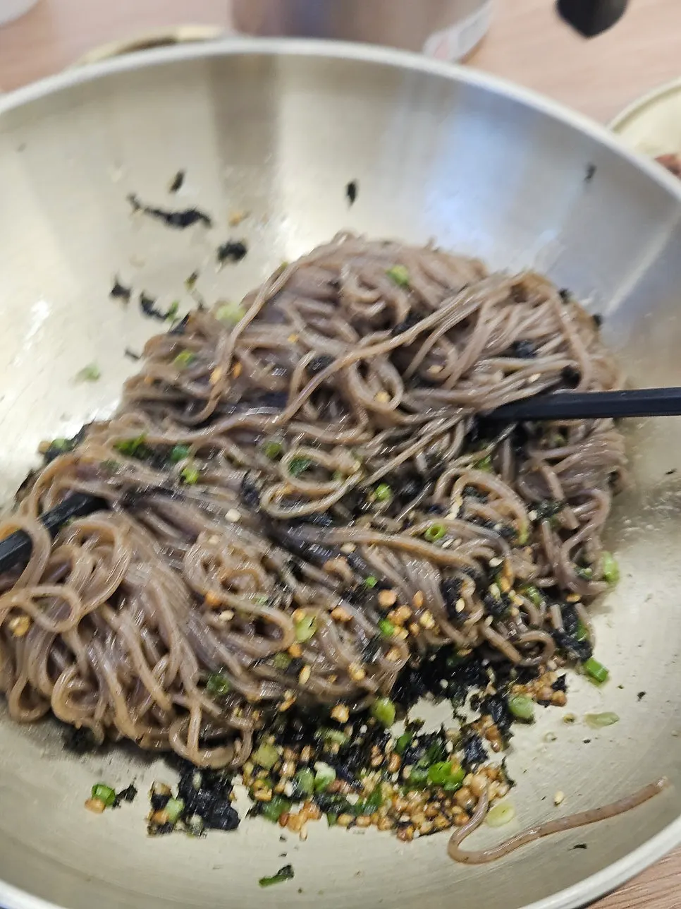 Close-up of perilla-oil makguksu topped with whole toasted seeds