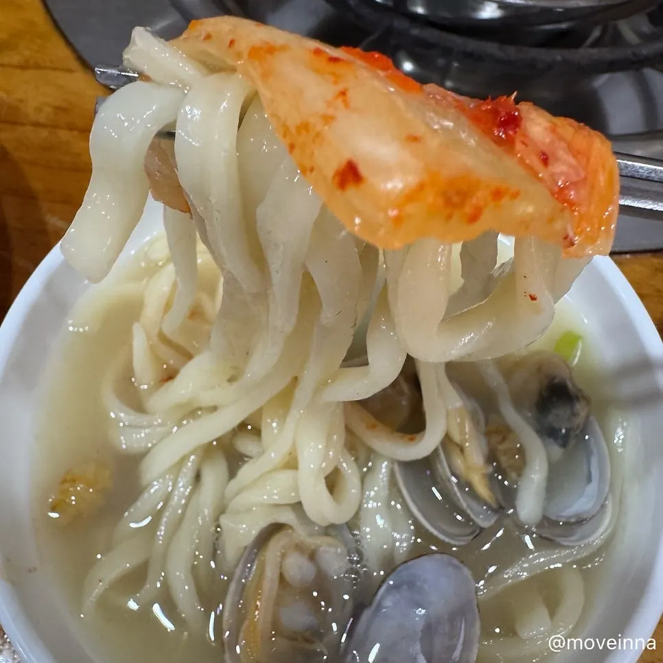 Well-fermented napa cabbage kimchi placed on top of the kalguksu noodles