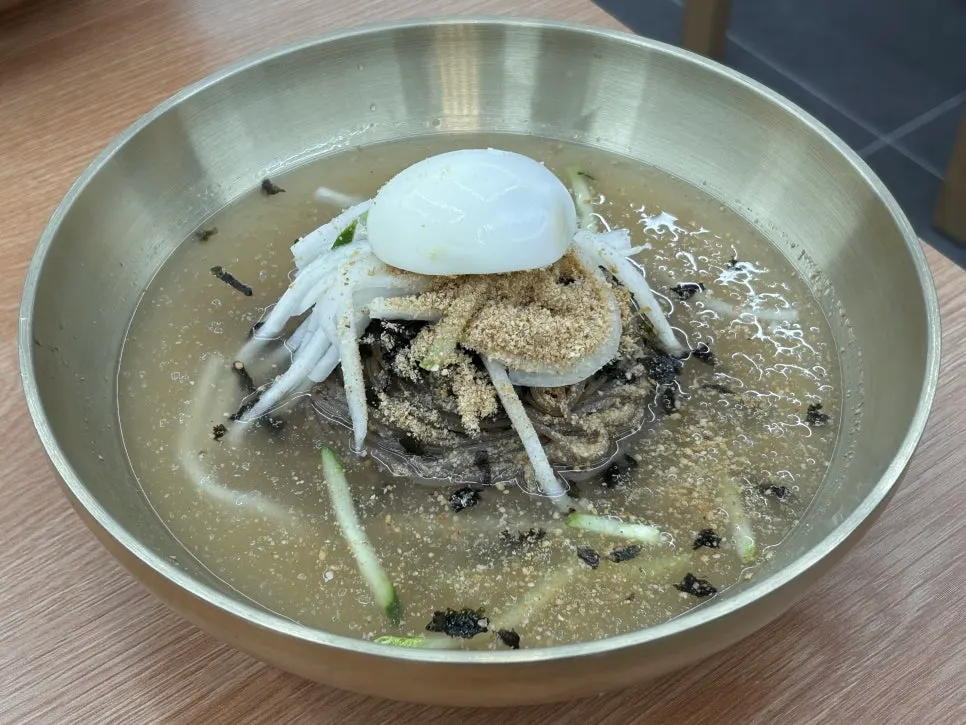 Dongchimi makguksu topped with garnish and perilla powder