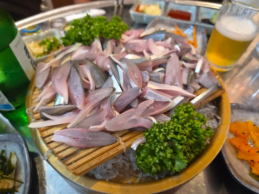 Gizzard shad sashimi served with ice on bamboo matting in a brass bowl