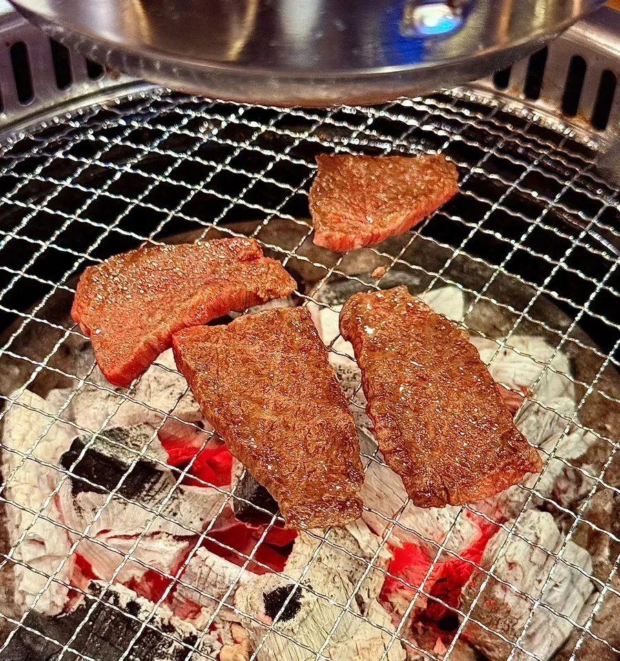 A piece of well-marbled hanwoo sizzling with rendered fat on the grill
