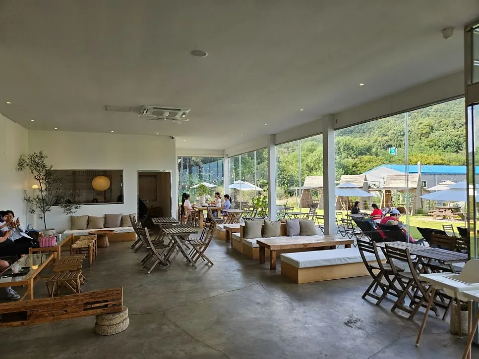 Sisup's interior with high ceilings, floor-to-ceiling windows, and forest views