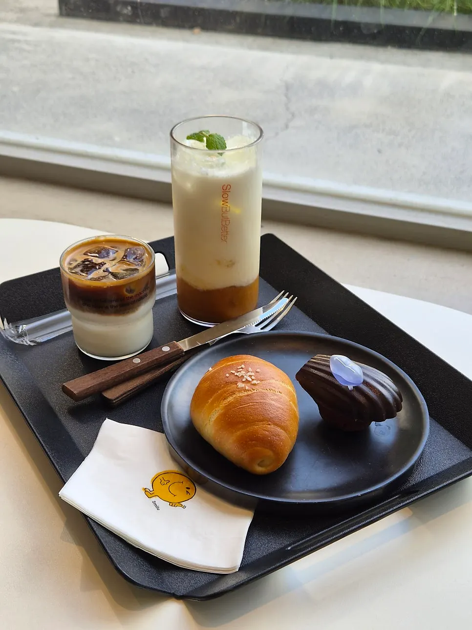 A tray with Barrel White, peach yogurt latte, salt bread, and Ringle chocolate madeleine