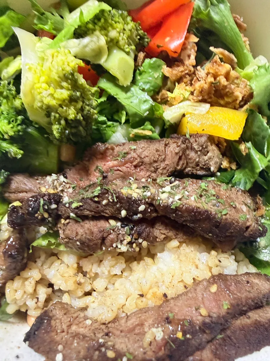 Hanger steak bowl with brown rice and vegetables underneath