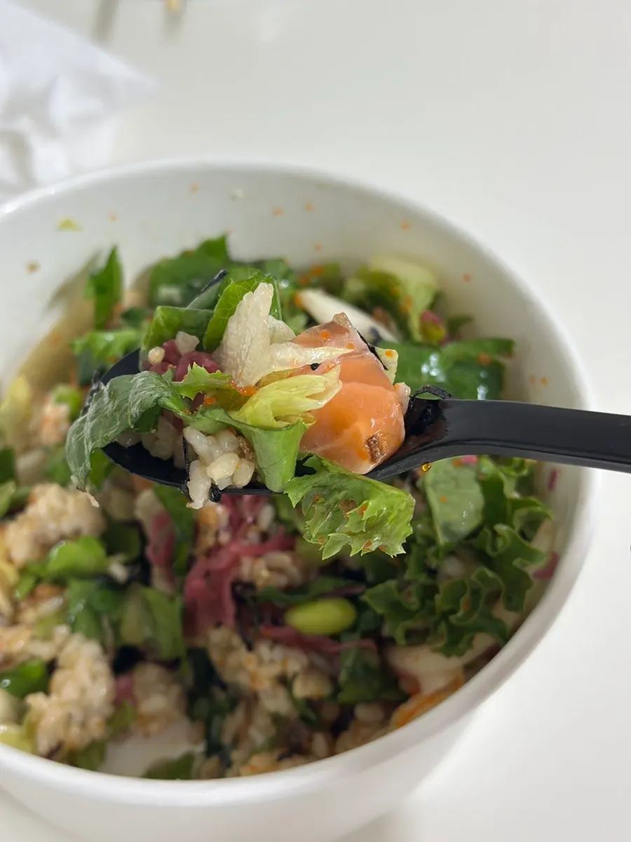 A bite of salmon poke with salmon, rice, and vegetables together