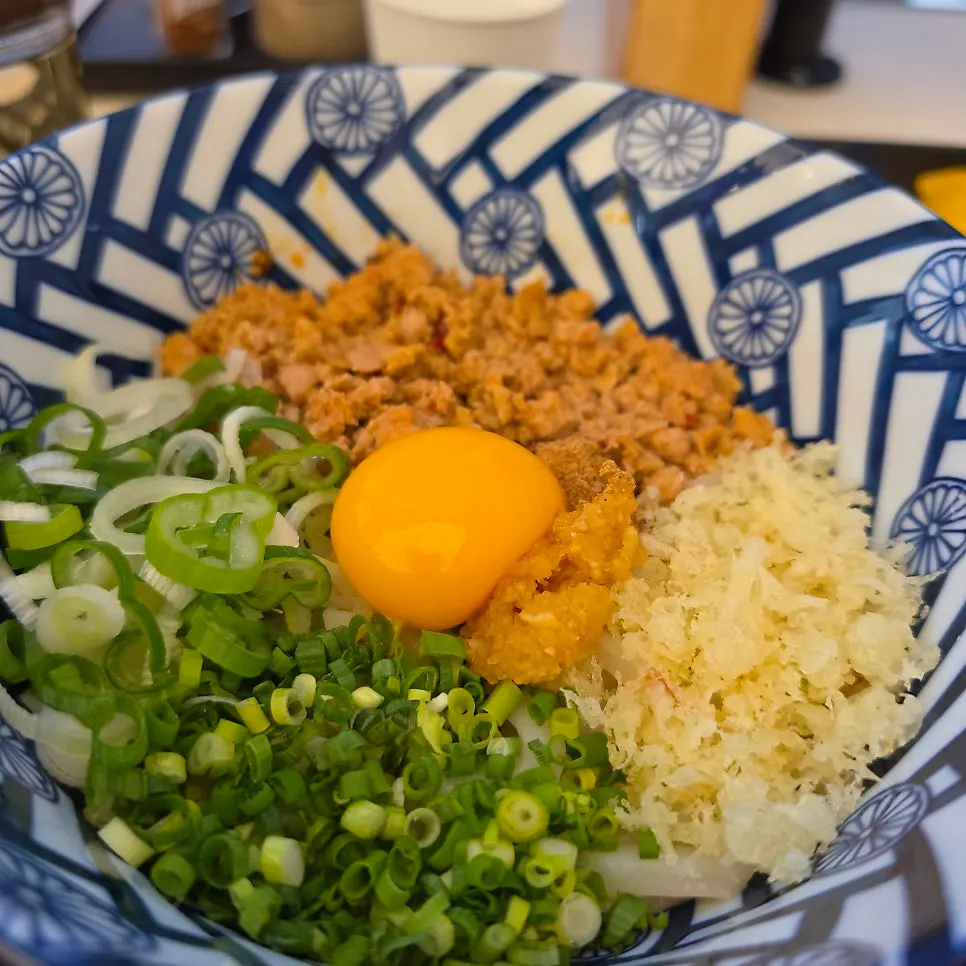 Udon noodles, broth, and beef loaded on a spoon