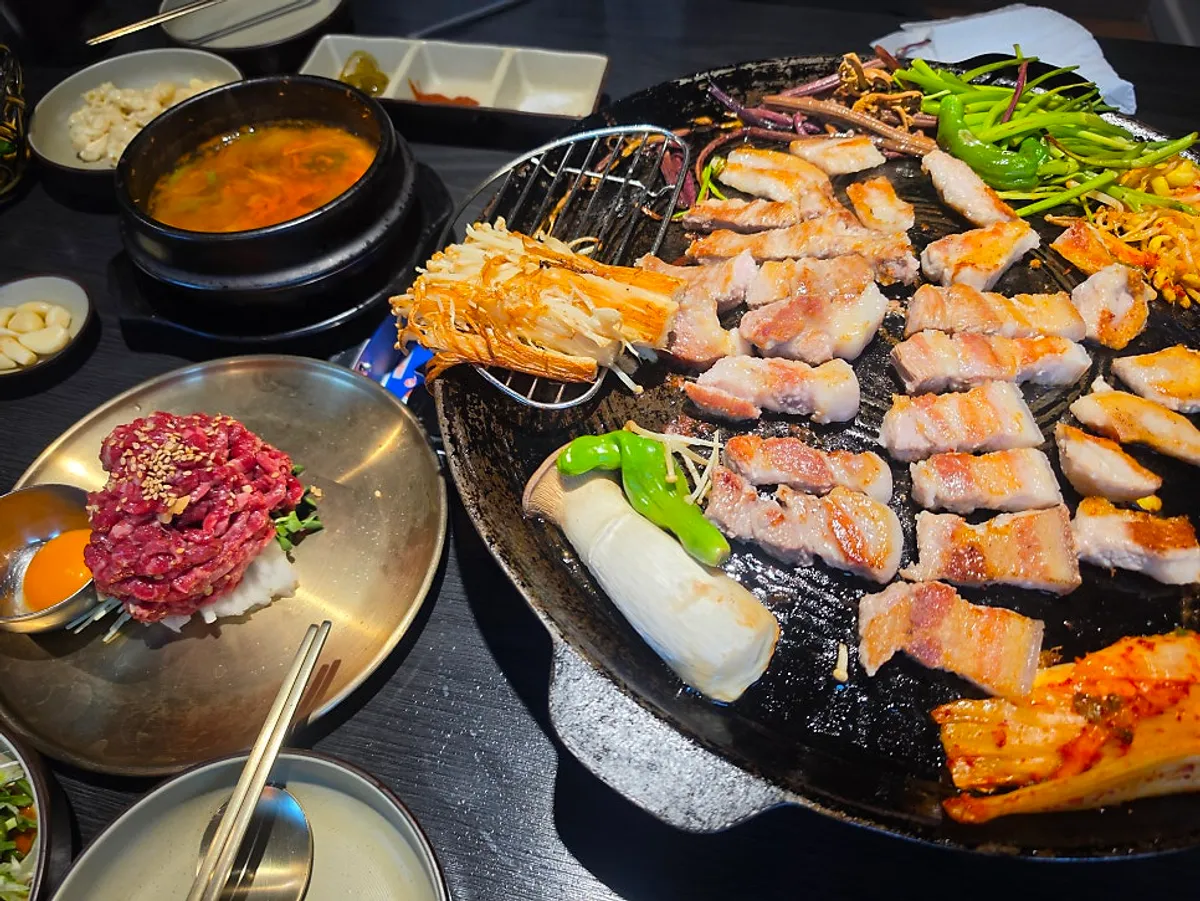 Side dishes including green onion kimchi and water dropwort served with the meat