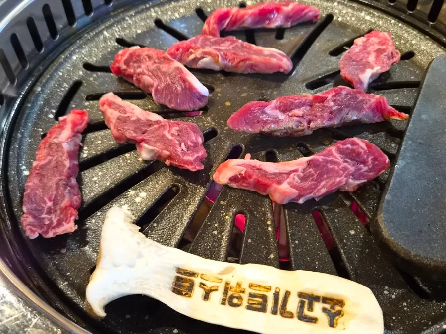 A plate of raw beef next to the grill