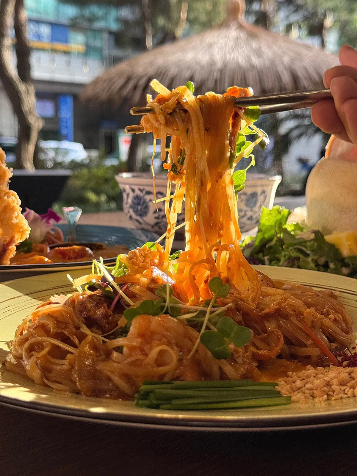 Chewy pad thai noodles lifted with chopsticks