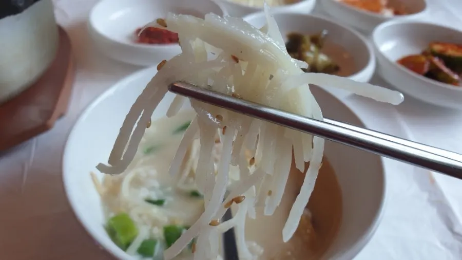 A spoonful of pollack flesh lifted from the soup