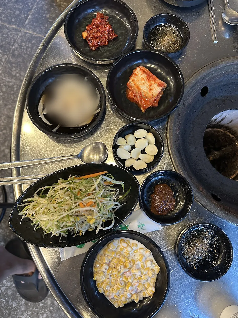 Table setting with scallion salad, scallop jeotgal, and other side dishes