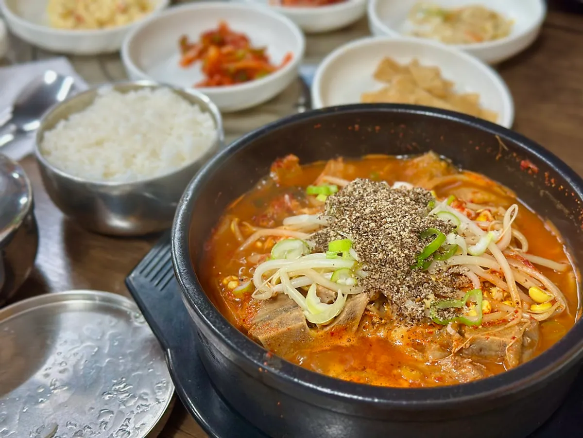 A full table setting with Gwandongjip's ppyeohaejangguk in an earthenware pot