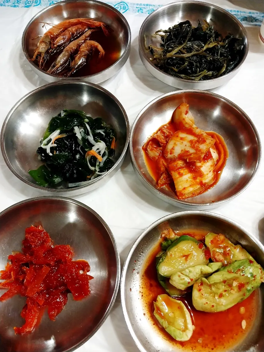 Plates of soy-marinated shrimp and buji kkaengi namul side dishes