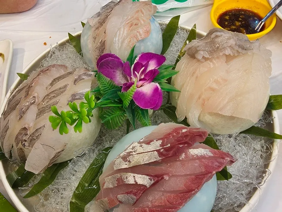 Chopsticks lifting a piece of chewy sashimi