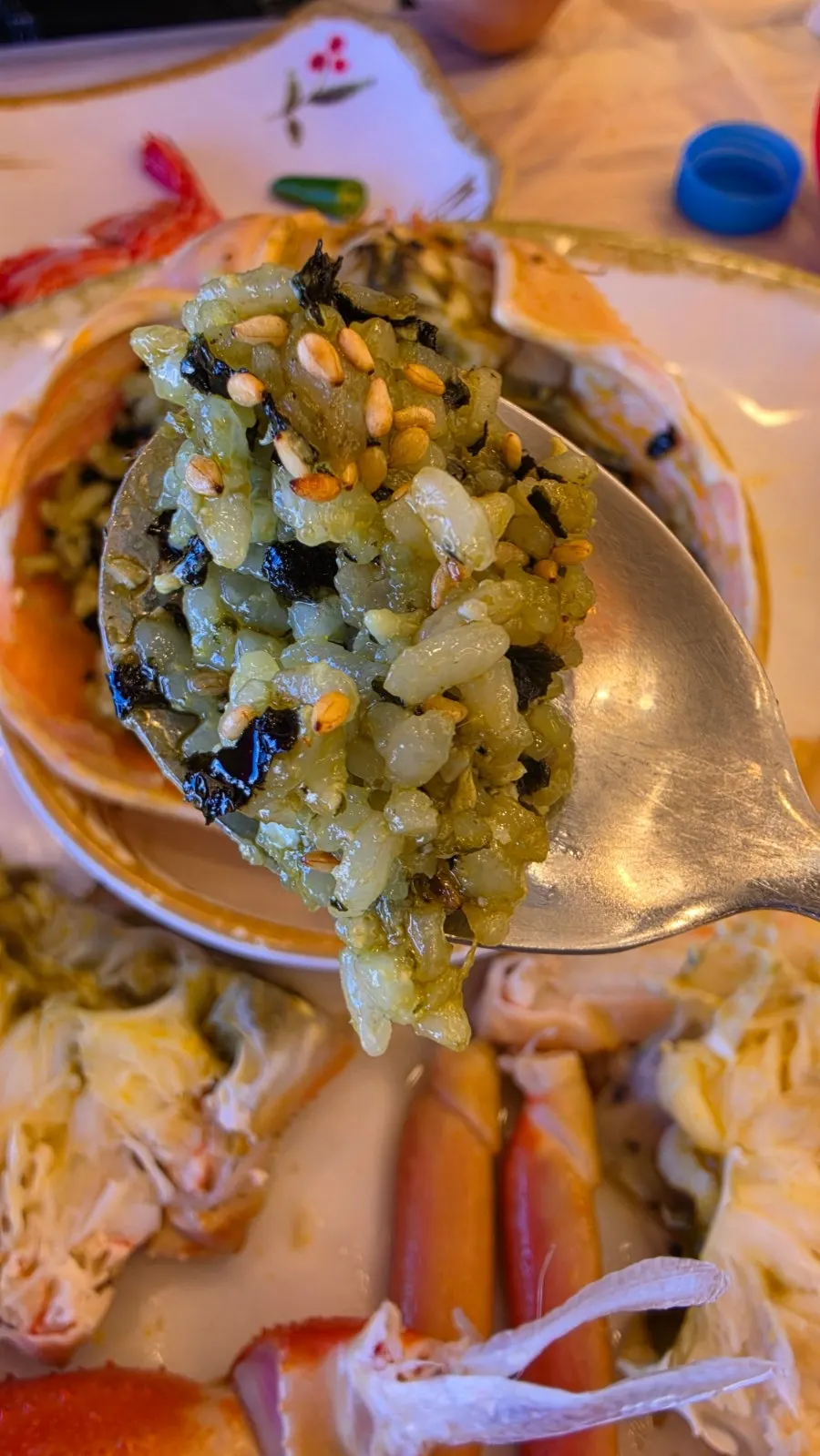 A spoonful of tomalley fried rice topped with seaweed flakes and sesame seeds