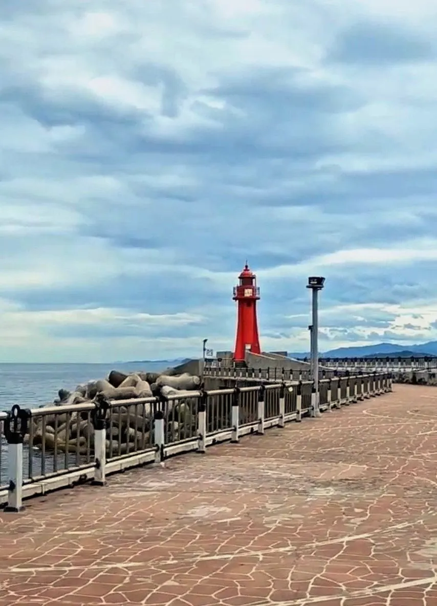 Breakwater walking path and red lighthouse at Daepo Port