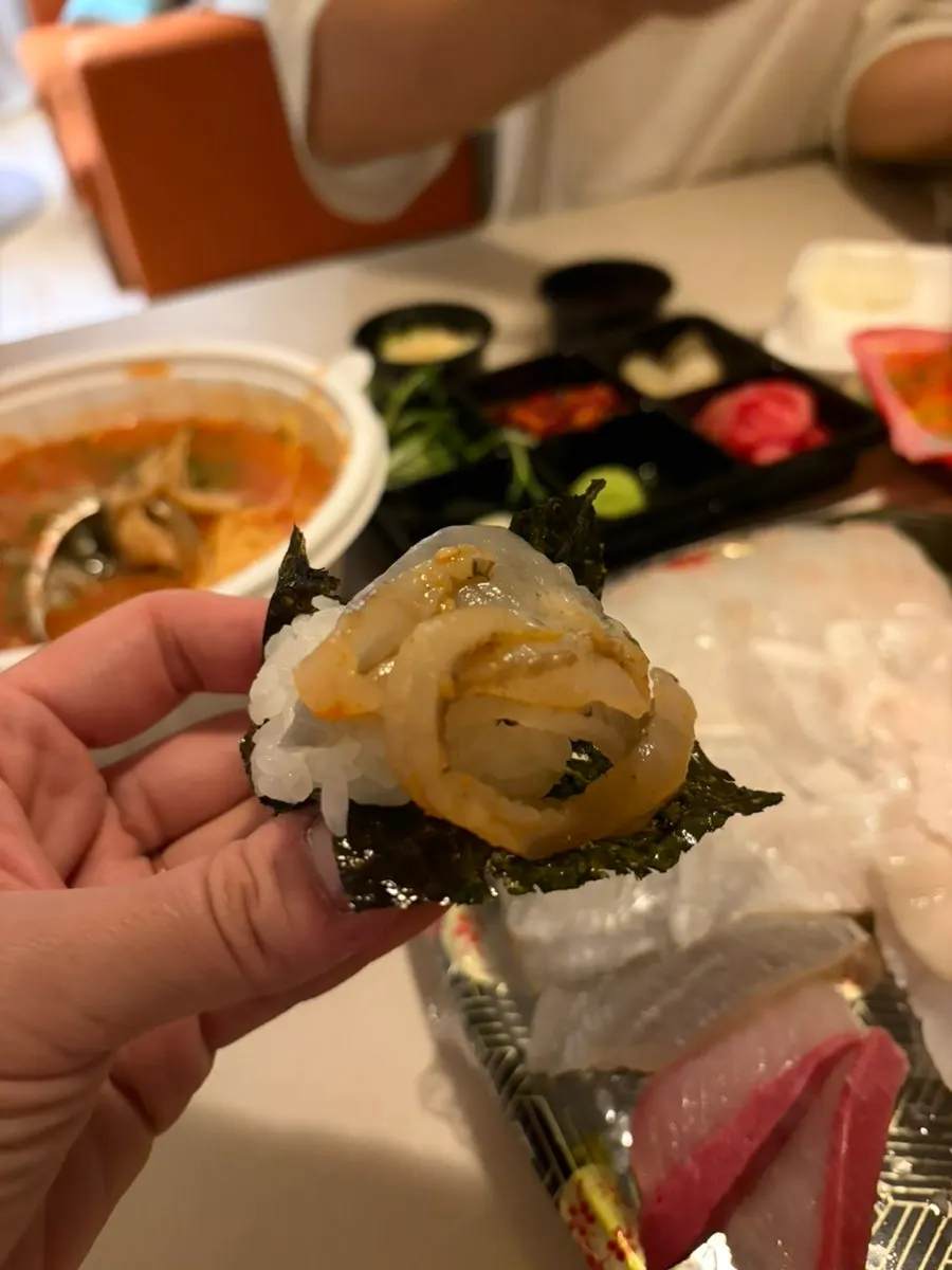 A wrap bite topped with kimchi, sashimi, and mulhoe