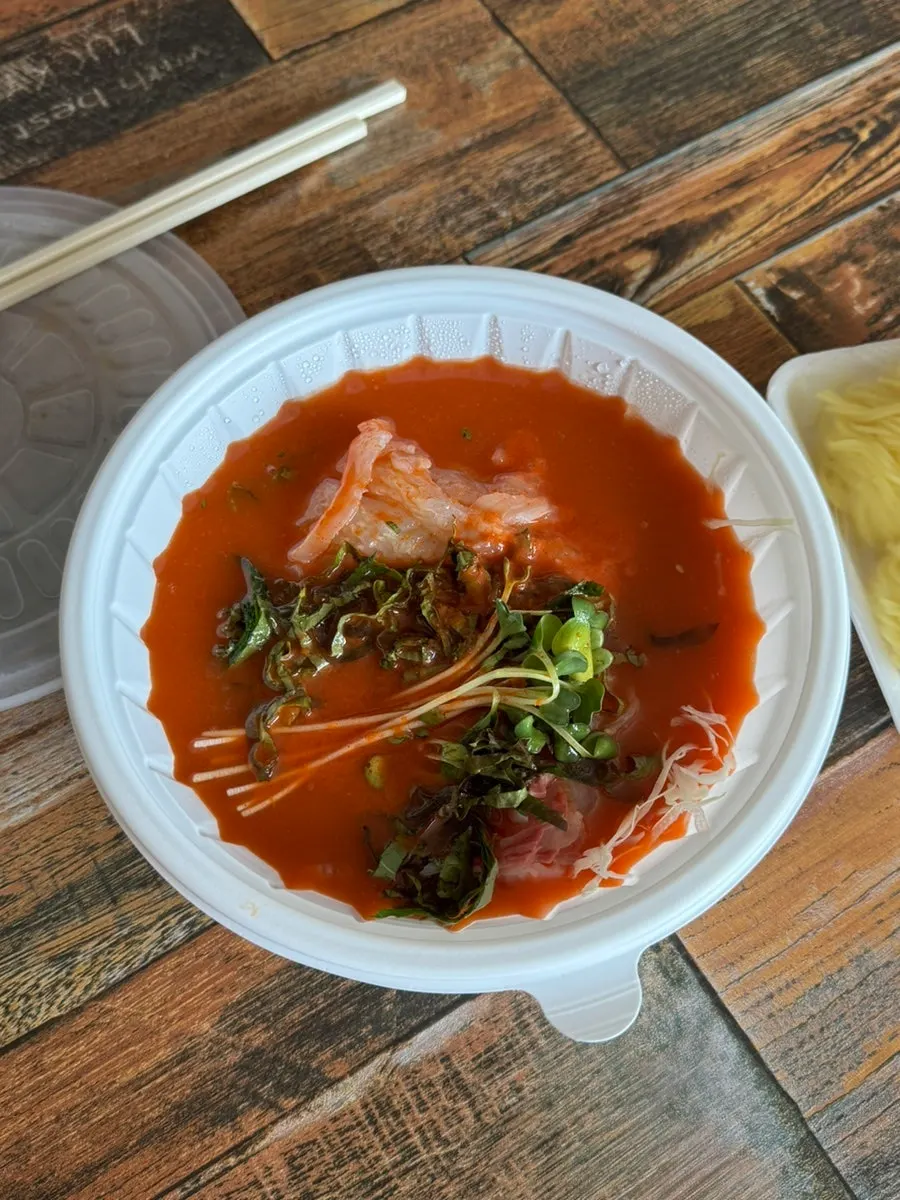 A piece of sashimi dipped in ssamjang and garlic