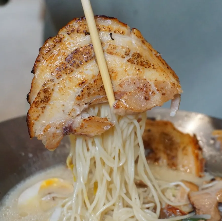 Soft-boiled egg yolk mixing into the broth