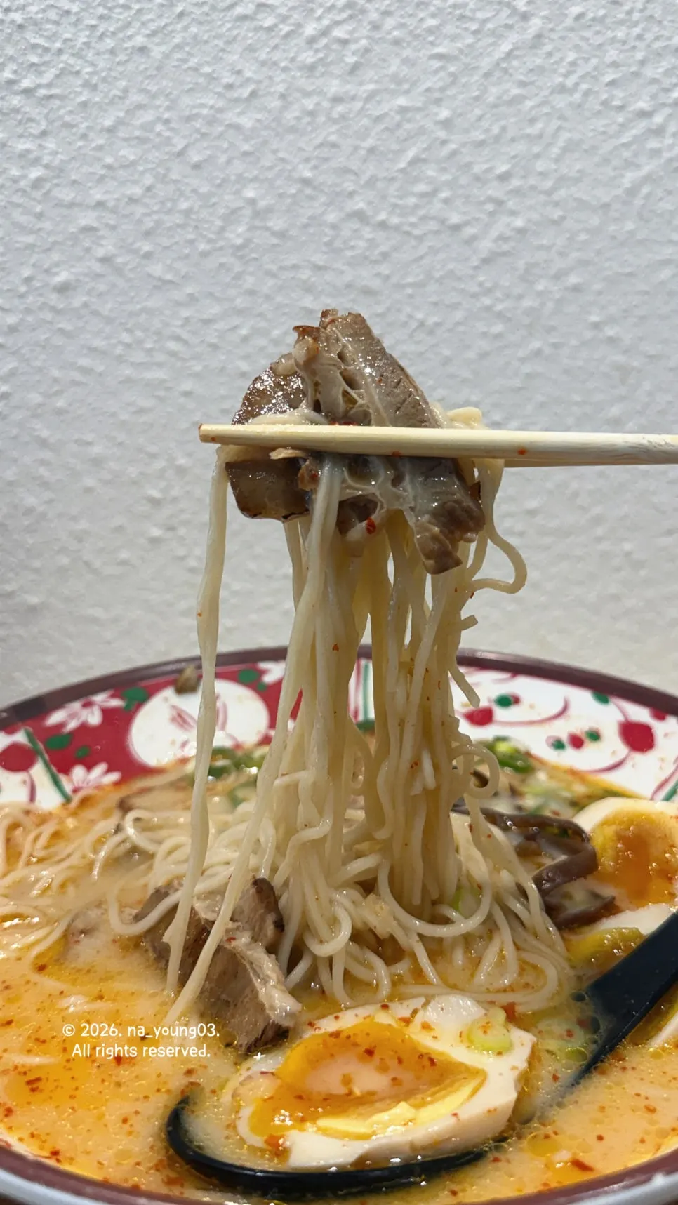 Tender chashu lifted with chopsticks