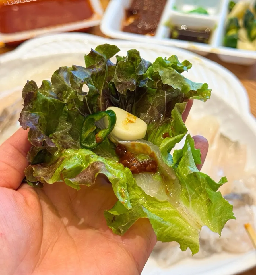 A bite of sashimi wrapped in lettuce