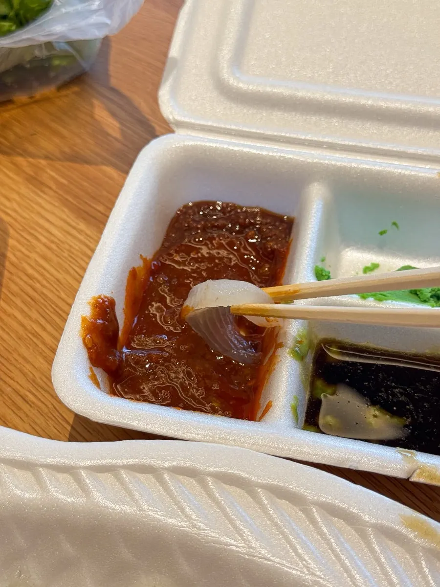 A piece of sashimi dipped in vinegar-chili sauce